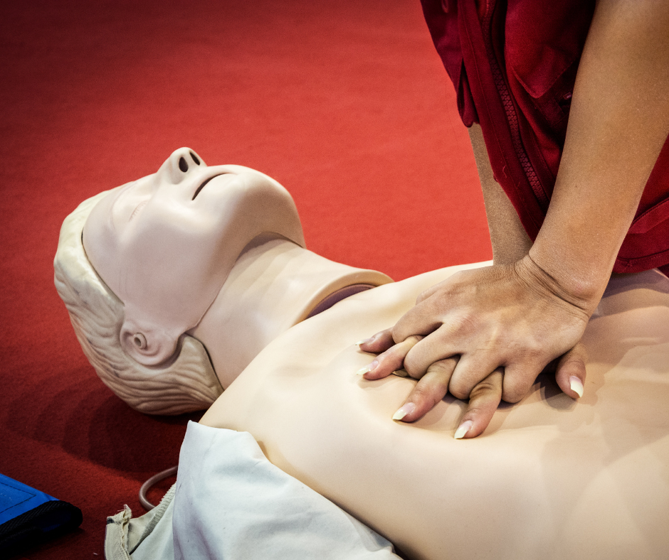Zdjęcie przedstawia człowieka wykonującego ćwiczenia pierwszej pomocy na fantomie