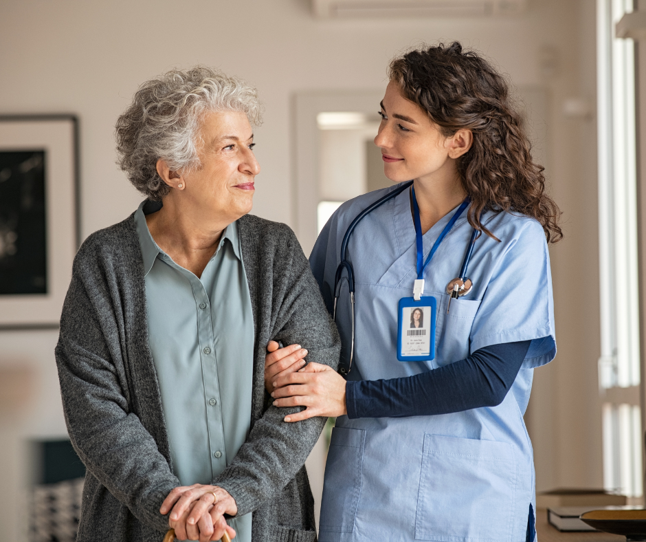 Zdjęcie przedstawia starszą kobietę prowadzoną przez pracownika domu opieki.